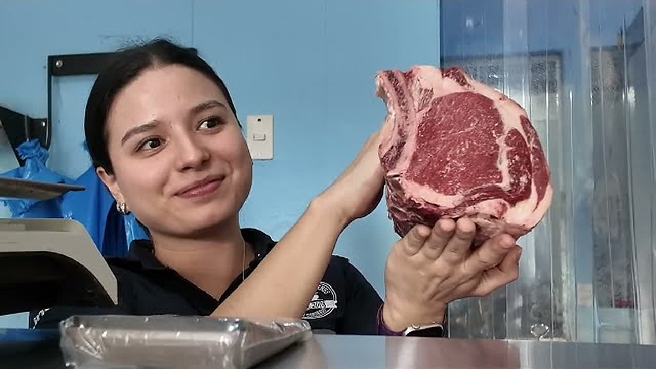 Butcher holding up a ribeye steak at a local butcher shop in Costa Rica